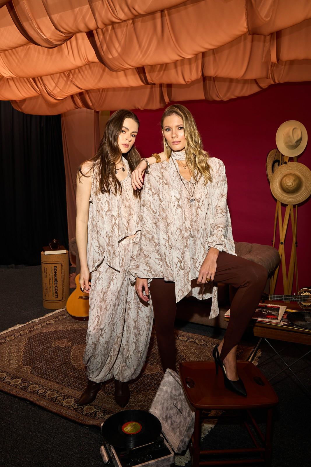 Two models in printed looks under a draped fabric ceiling